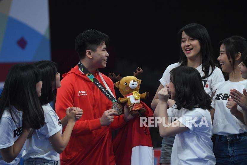 Atlet Wushu Indonesia Edgar Xavier Marvelo menerima ucapan terima kasih dari member JKT 48 usai  prosesi penyerahan medali cabang olahraga Wushu Changquan Putra di Hall B, JIE Expo Kemayoran, Jakarta, Ahad (19/8).