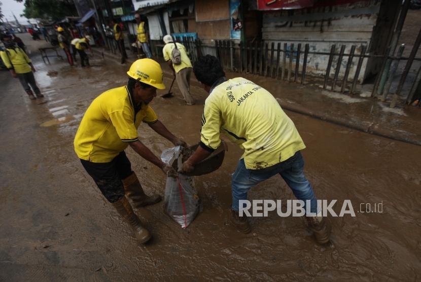 Petugas Bina Marga mengangkut lumpur pascabanjir di Ruas Jalan Jatinegara Barat, Jakarta, Rabu (7/2).