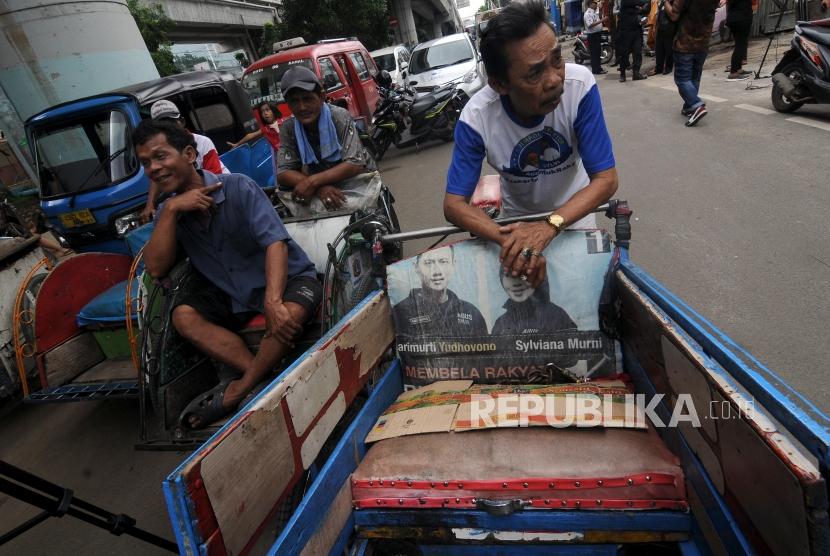 Tukang becak saat menunggu untuk didata oleh petugas di kolong flyover Bandengan Utara, Pekojan, Tambora, Jakarta Barat, Jumat (26/1).