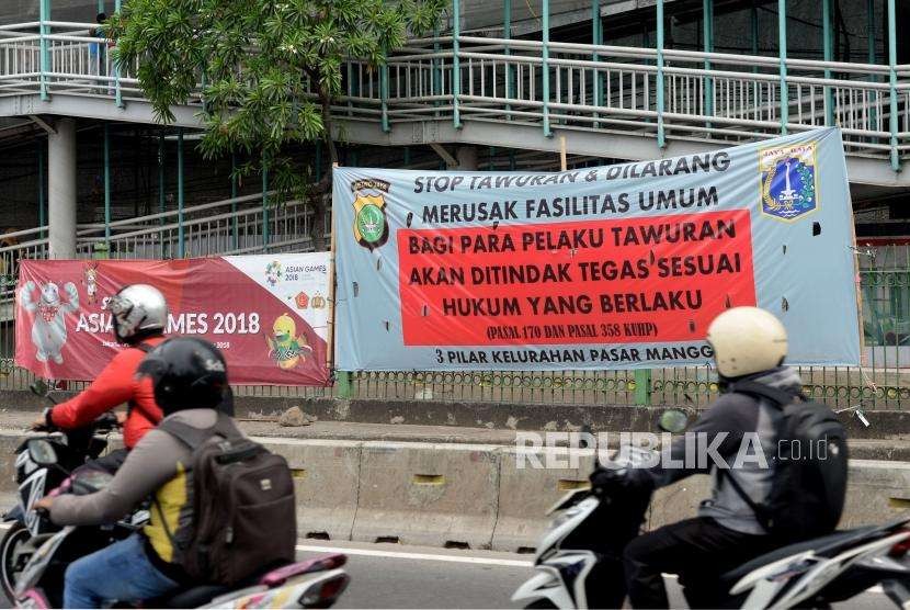 Pengendara sepeda motor melintas di dekat spanduk bertuliskan himbauan stop tawuran di Kawasan Pasar Rumput, Jakarta.