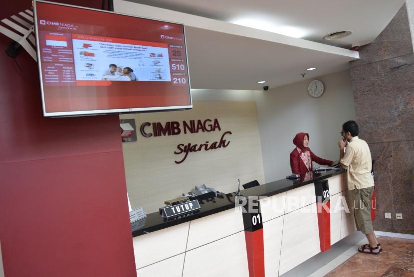 Petugas melayani transaksi nasabah di Bank CIMB Niaga Syariah, Jakarta, Rabu (7/11).