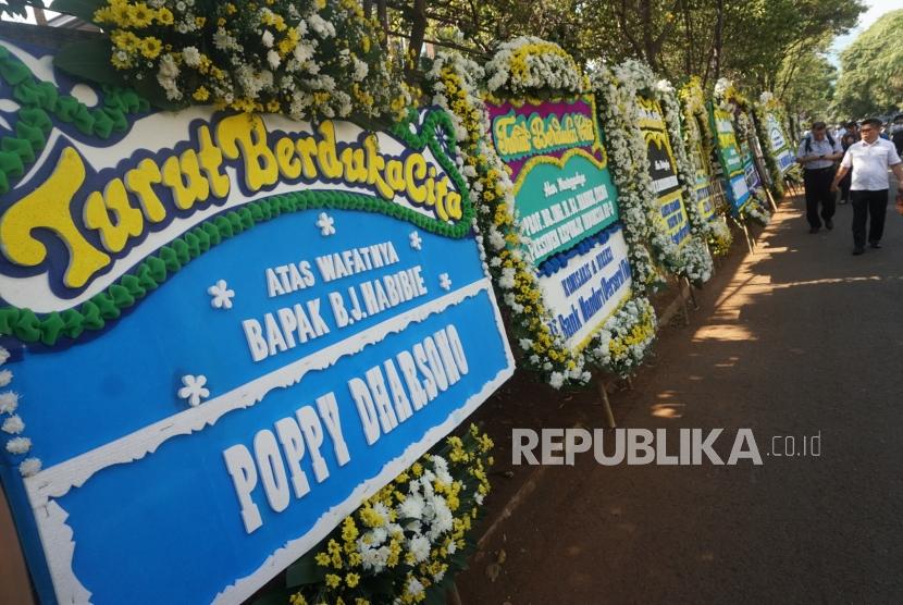 Sejumlah pelayat berjalan di depan karangan bunga ucapan belasungkawa atas wafatnya Presiden ke-3 Republik Indonesia BJ Habibie di rumah duka, kawasan Patra Kuningan, Jakarta, Kamis (13/9).