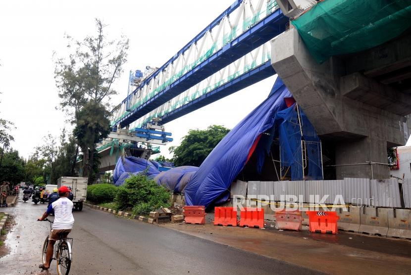 Kendaraan melintas di samping konstruksi proyek Light Rapid Transit (LRT) yang roboh di kawasan Jalan Raya Kayu Putih, Pulogadung, Jakarta Timur, Senin (22/1).