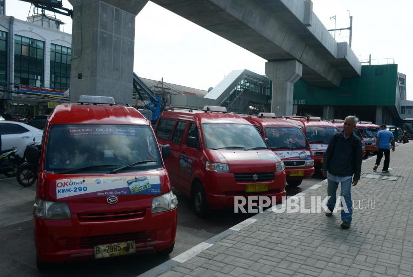 Warga melintas di dekat angkutan umum (angkot) mangkal di kawasan Stasiun MRT Lebak Bulus, Jakarta, Kamis (28/3).