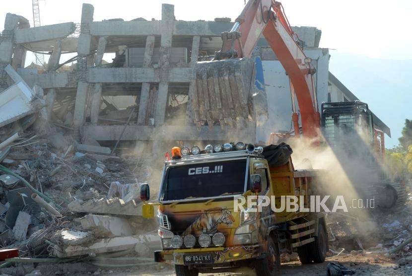 Sejumlah alat berat menyimpan reruntuhan bangunan Hotel Roa Roa ke truk saat proses evakuasi di Palu, Sulawesi Tengah, Senin (1/10).