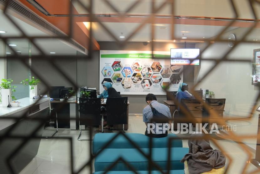 Karyawan melayani transaksi nasabah di kantor layanan BNI Syariah, Jakarta, Selasa (22/1).