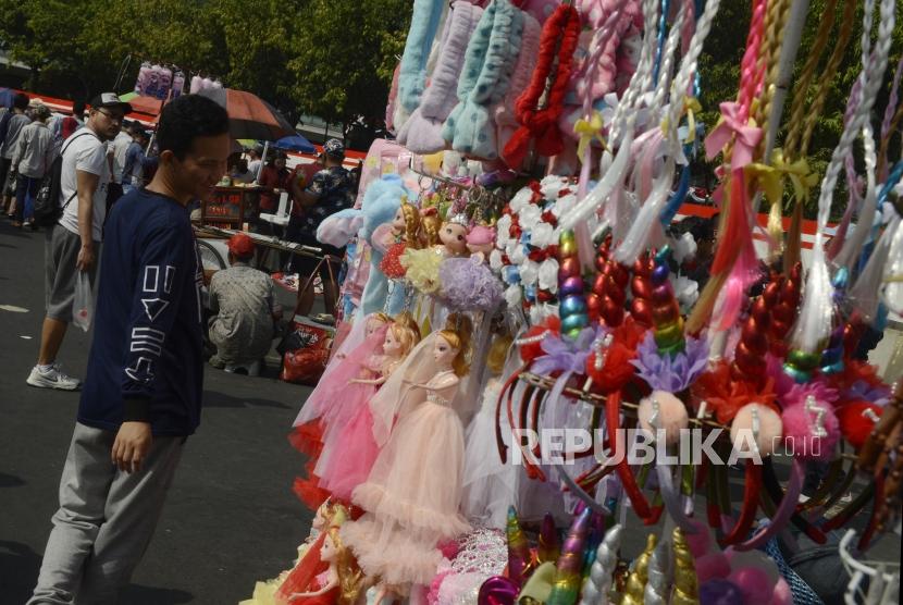Warga saat akan membeli aksesoris yang dijual pedagang kaki lima pada hari bebas kendaraan bermotor di kawasan Bundaran HI, Jakarta, Ahad (25/8).