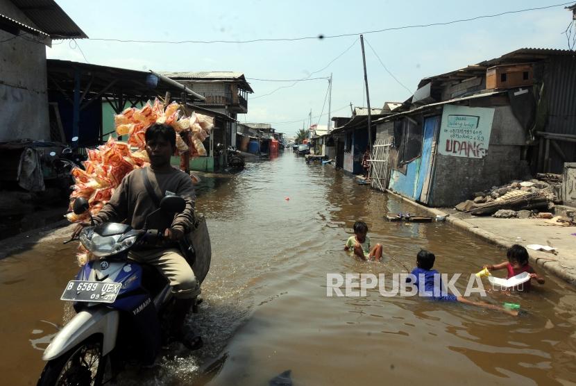 Anak-anak bermain saat terjadi banjir rob yang menggenangi kawasan Muara Angke, Jakarta Utara, Rabu (3/1).