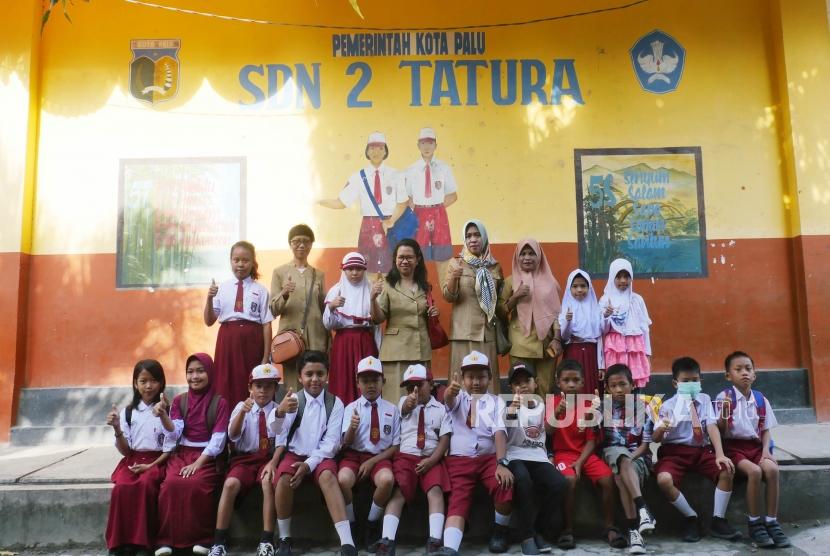 Sejumlah siswa dan guru SD Negeri 2 Tatura Palu, Sulawesi Tengah berfoto bersama di halaman seklahnya, Senin (15/10).