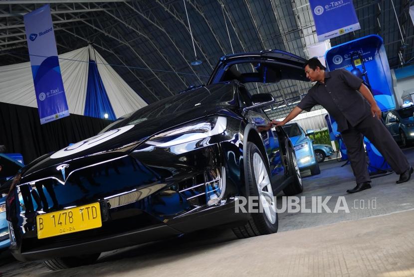 TAKSI LISTRIK. Awak armada e-Taxi Silver Bird membuka pintu penumpang mobil Tesla X75 di Port Charging Bluebird di Jakarta, Senin (22/4).