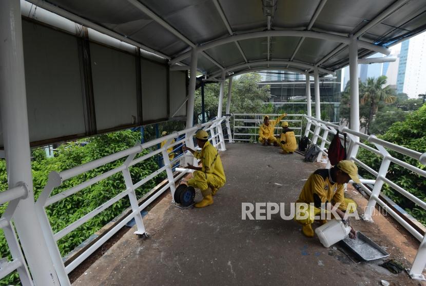 Petugas Dinas Bina Marga DKI Jakarta saat melakukan perawatan jembatan penyeberangan orang (JPO) di kawasan Karet, Jakarta, Senin (18/2).