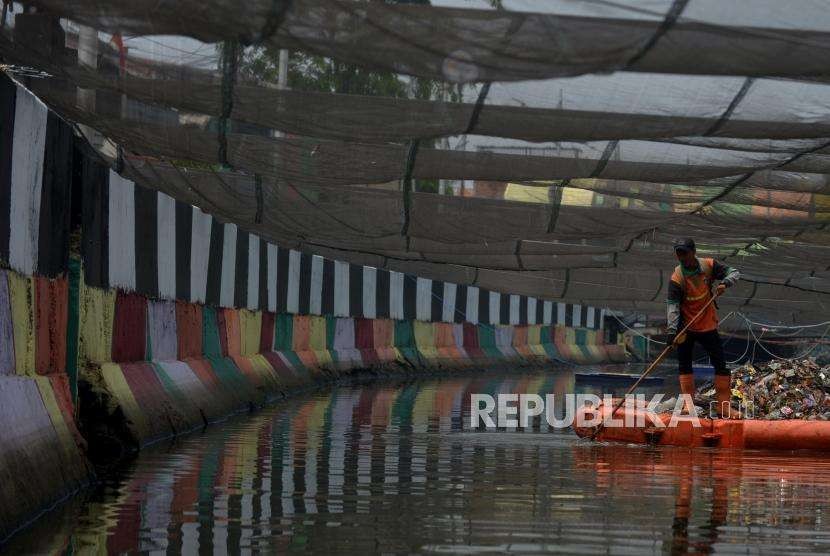 Petugas PPSU membersihkan Kali Item/ Kali Sentiong yang ditutupi jaring di kawasan Wisma  Atlet, Kemayoran Jakarta Pusat, Jumat (5/10).