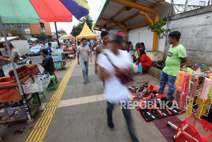 Warga melintasi para pedagang kali lima (PKL) di trotoar kawasan Tanah Abang, Jakarta, Kamis (14/12).