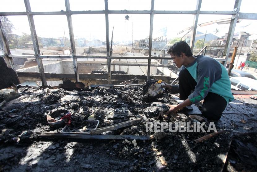 Warga membersihkan puing-puing bangunan pasca kebakaran di Kawasan Perumahan Taman Kota, Jakarta, Jumat (30/3).