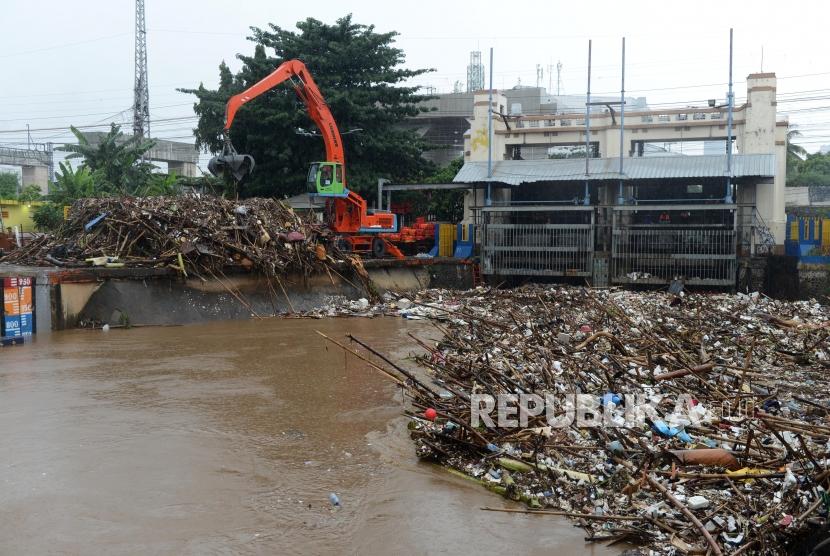 Pekerja menggunakan alat berat mengangkut sampah yang mengalir ke Pintu Air Manggarai. BPBD menyebutkan hingga kini belum ada pintu air di DKI berstatus awas