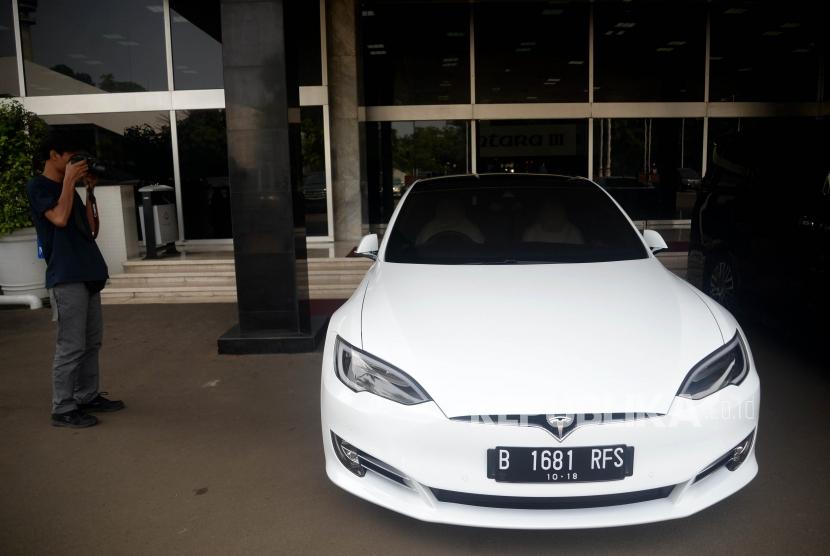 Jurnalis mengambil gambar mobil listrik Tesla yang terparkir di depan Gedung Nusantara III, Kompleks Parlemen, Jakarta, Selasa (3/7).