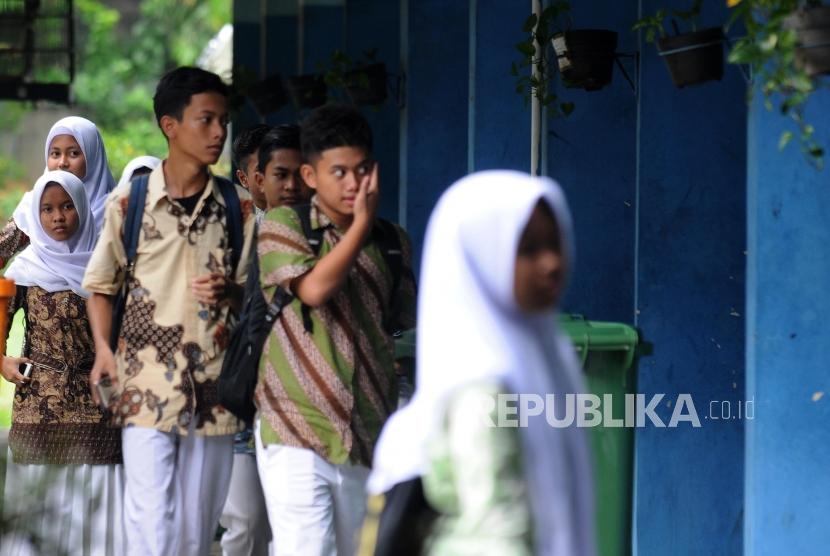 Pelajar saat menunggu dijemput orang tuanya usai pelaksanaan Ujian Nasional Berbasis Komputer (UNBK) di SMP Negeri 212 Jakarta, Cilandak, Jakarta, Kamis (26/4).