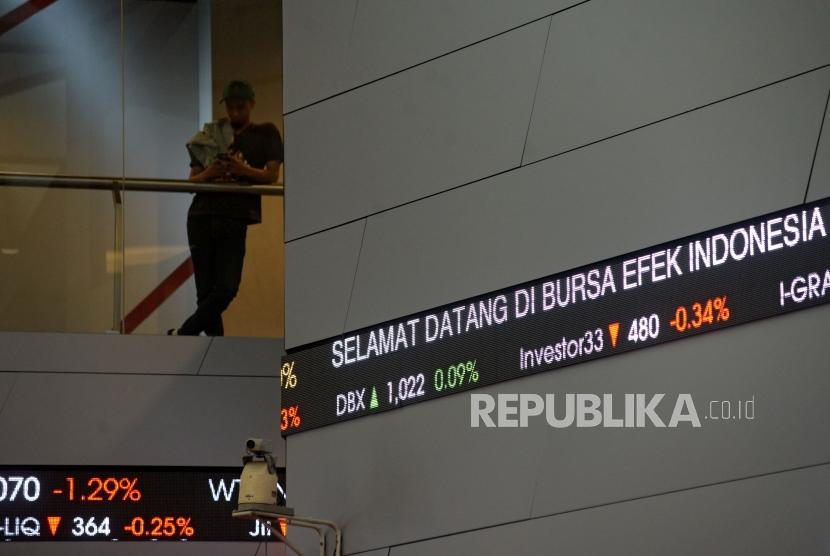 Karyawan melintas di dekat layar elektronik Indeks Harga Saham Gabungan (IHSG) di Gedung Bursa Efek Indonesia (BEI) Jakarta, Selasa (20/2).