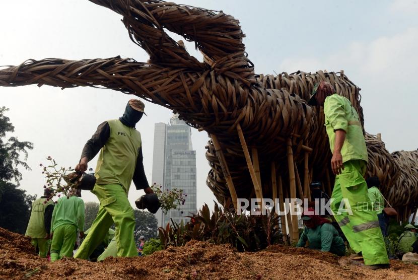 Petugas Suku Dinas Kehutanan Kota Administrasi Jakarta Pusat saat mengganti tanaman rusak yang berada di sekeliling instalasi seni bambu Getah Getih di kawasan Bundaran HI, Jakarta, Ahad (23/6).