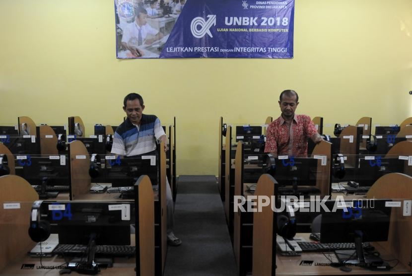 Staf guru mengecek komputer yang akan digunakan untuk Ujian Nasional Berbasis Komputer (UNBK) di SMA Negeri 40, Jakarta Utara, Jumat (6/4).