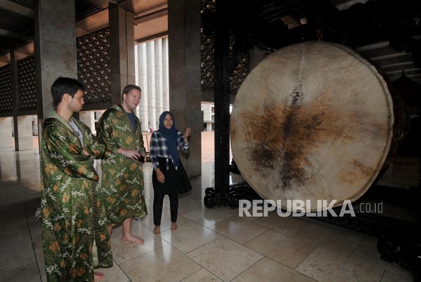 Pemandu wisata memberikan penjelasan kepada turis mancanegara di Masjid Istiqlal, Jakarta, Ahad (28/1).