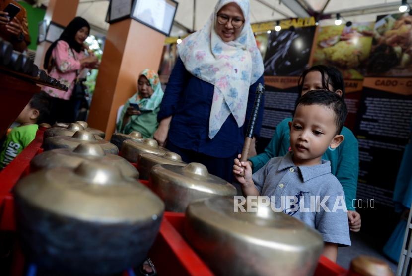 Anak-anak saat mencoba alat kesenian betawi pada acara Festival Warisan Budaya Tak Benda di kawasan Setu Babakan, Jakarta, Ahad (28/4).