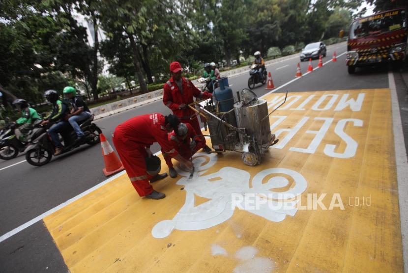 Pekerja mengecat jalur kuning khusus sepeda motor di Kawasan Jalan Merdeka Barat, Jakarta, Rabu (17/1).