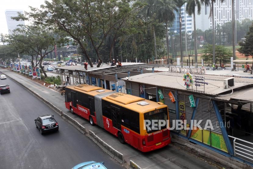 Bus Transjakarta melintas saat pekerja menyelesaikan perluasan Halte Transjakarta Gelora Bung Karno di Kawasan Sudirman, Jakarta, Kamis (19/7).