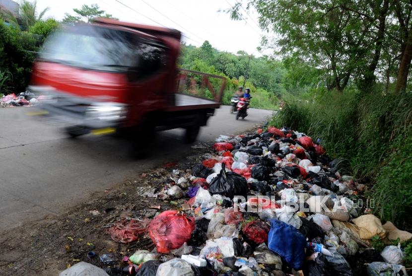 Sejumlah kendaraan melintas didekat sampah yang dibuang di pinggir jalan. (Ilustrasi)