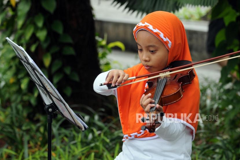 Anak-anak belajar memainkan alat musik biola di Taman Suropati, Menteng, Jakarta, Ahad (15/4).