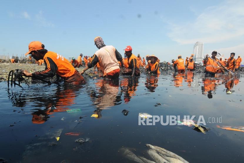 Sejumlah petugas saat membersihkan sampah yang menumpuk di Muara Angke, Jakarta Utara Senin (19/3).