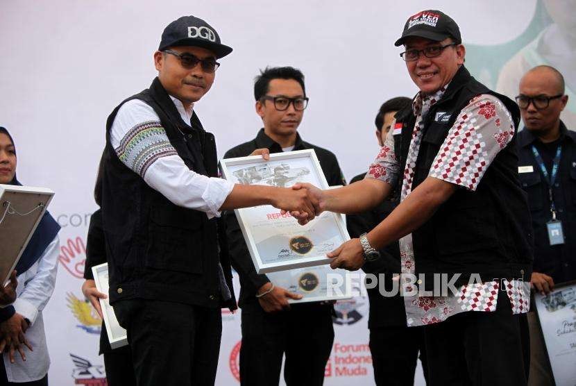 Dewan Syariah Yayasan Dompet Dhuafa Republika Izzudin Abdul Manaf (kanan) menyerahkan penghargaan kepada Pemimpin Redaksi Harian Republika Irfan Junaidi (kiri) saat acara pucak Milad ke-25 Dompet Dhuafa di Tugu Proklamasi, Jakarta, Sabtu (22/9).