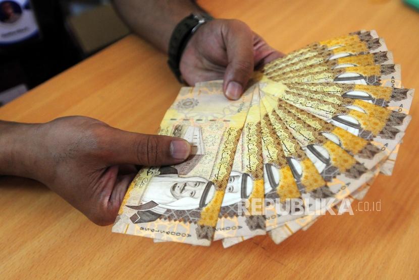 Petugas merapihkan mata uang Saudi Riyal di Asrama Haji Pondok Gede, Jakarta, Senin (23/7).