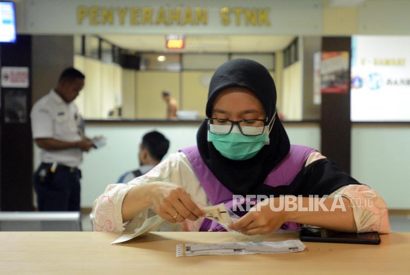 Warga mempersiapkan surat-surat saat melakukan pembayaran pajak kendaraan bermotor di Kantor Samsat Polda Metro Jaya, Jakarta, Jumat (16/11).