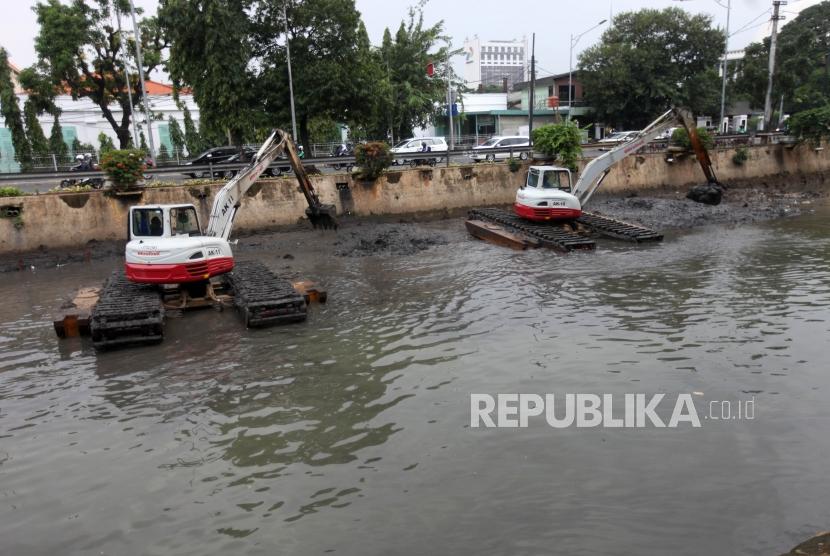 Petugas menggunakan alat berat mengeruk endapan sampah bercampur lumpur di aliran sungai Ciliwung, Kawasan Pasar Baru, Jakarta, Selasa (13/2).