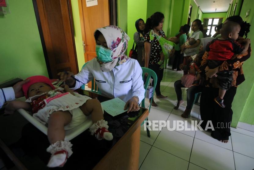 Balita saat ditimbang berat badannya sebelum melakukan imunisasi difteri di Puskemas Cimanggis, Depok, Jawa Barat, Rabu (6/12).
