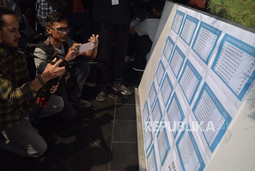Jurnalis mengambil gambar daftar nama penumpang pesawat Lion Air JT 610 di Posko Utama jatuhnya Pesawat Lion Air di Bandara Soekarno Hatta, Tangerang, Banten, Senin (29/10).