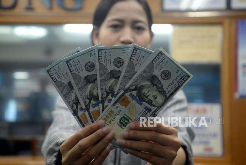 Petugas menunjukan pecahan dolar Amerika Serikat di salah satu gerai penukaran mata uang asing di Jakarta,Ahad (2/9).