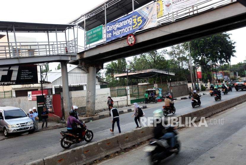 Warga melintas dibawah jembatan penyeberangan orang (JPO) yang rusak akibat ditabrak truk kontainer di Halte bus Transjakarta Dispenda Samsat barat, Daan Mogot Jakarta, Senin (3/9).