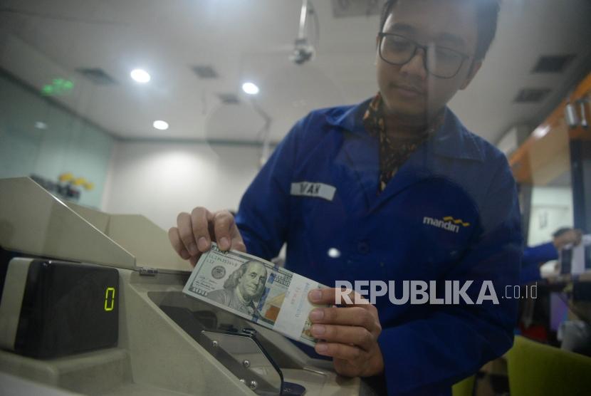 Karyawan menghitung tumpukan uang dolar Amerika Serikat di Cash Center Bank Mandiri, Jakarta, Senin (23/7).