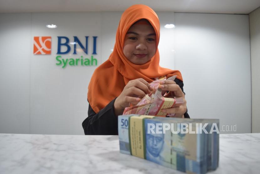 Karyawan mengitung uang nasabah di kantor layanan BNI Syariah, Jakarta, Senin (5/11).