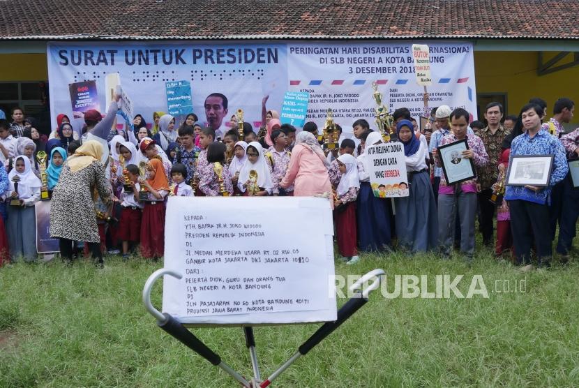 Para pelajar membawa piala dan poster bersiap untuk berfoto bersama usai membuat surat untuk Presiden Joko Widodo (Jokowi) pada saat peringatan Hari Disabilitas Internasional, di Sekolah Luar Biasa Negeri (SLBN) A, Kota Bandung, Kamis (29/11).