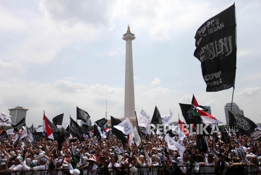Sejumlah massa mengibarkan bendera tauhid saat mengikuti reuni aksi 212 di Lapangan Monumen Nasional, Jakarta, Ahad, (2/12).