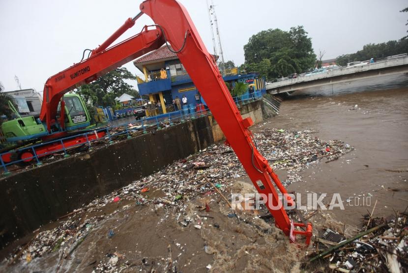 Petugas menggunakan alat berat mengangkut sampah di Pintu air Manggarai, Jakarta, Senin (5/2).