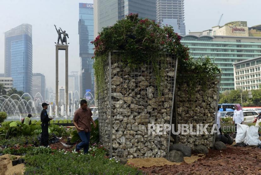 Warga melintas di dekat instalasi batu gabion di Bundaran HI, Jakarta, Jumat (23/8).