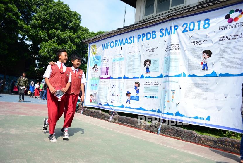 Dua siswa melintasi baliho informasi  Perimaan Peserta Didik Baru (PPDB) di SMPN 34 Bandung (ilustrasi)