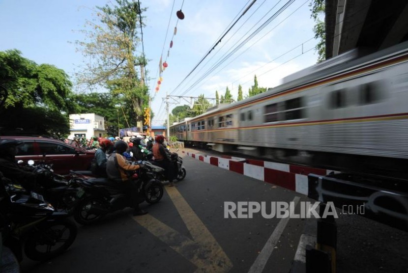 Menunggu. Pengendara kendaraan roda dua  menunggu teerbukanya pintu perlintasan kereta sebidang di Jalan K.H Mansyur, Jakarta, Rabu (1/11).