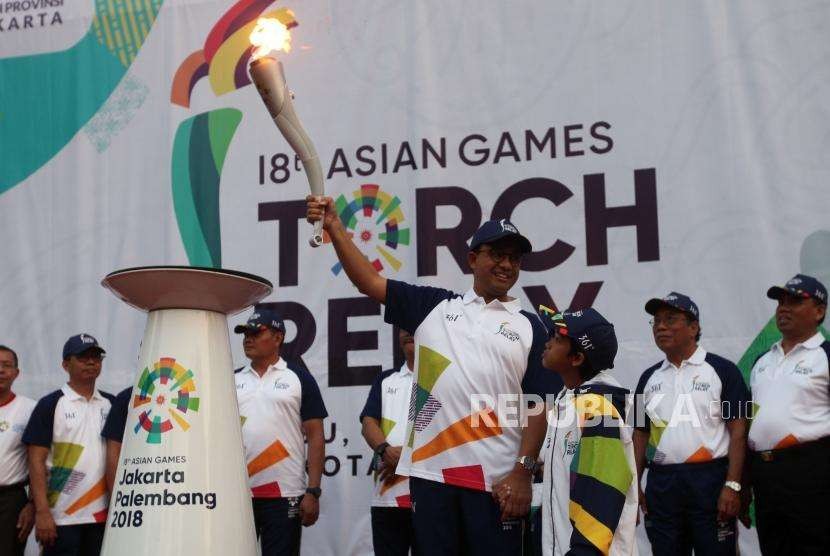 Gubernur DKI Jakarta Anies Baswedan membawa obor saat Torch Relay Asian Games 2018 di Kawasan Kramat Jati, Jakarta, Rabu (15/8).