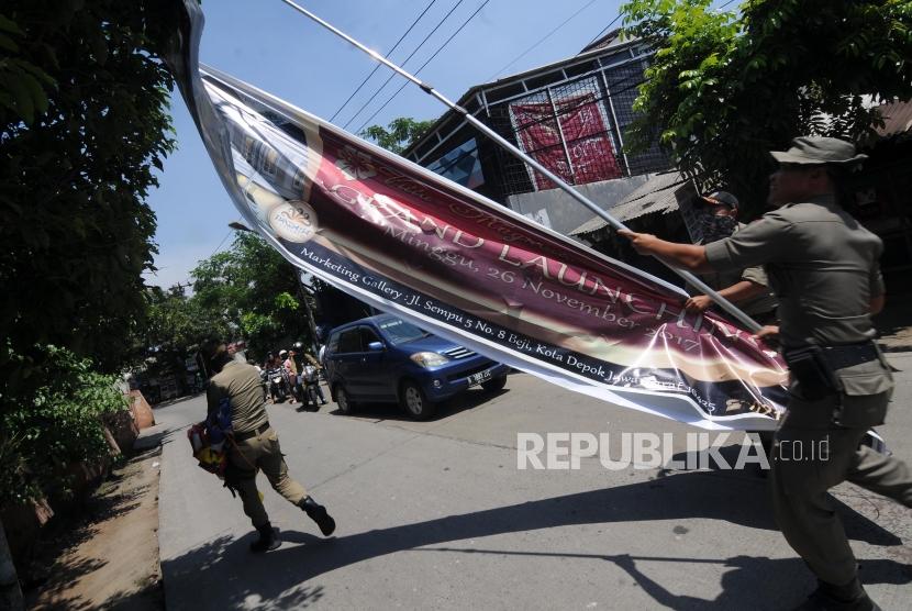 Petugas Satpol PP mencabut spanduk yang terpasang di kawasan Beji, Depok, Jawa Barat, Rabu (6/12).