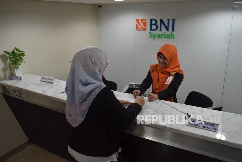 Karyawan melayani transaksi nasabah di kantor layanan BNI Syariah, Jakarta, Senin (5/11).